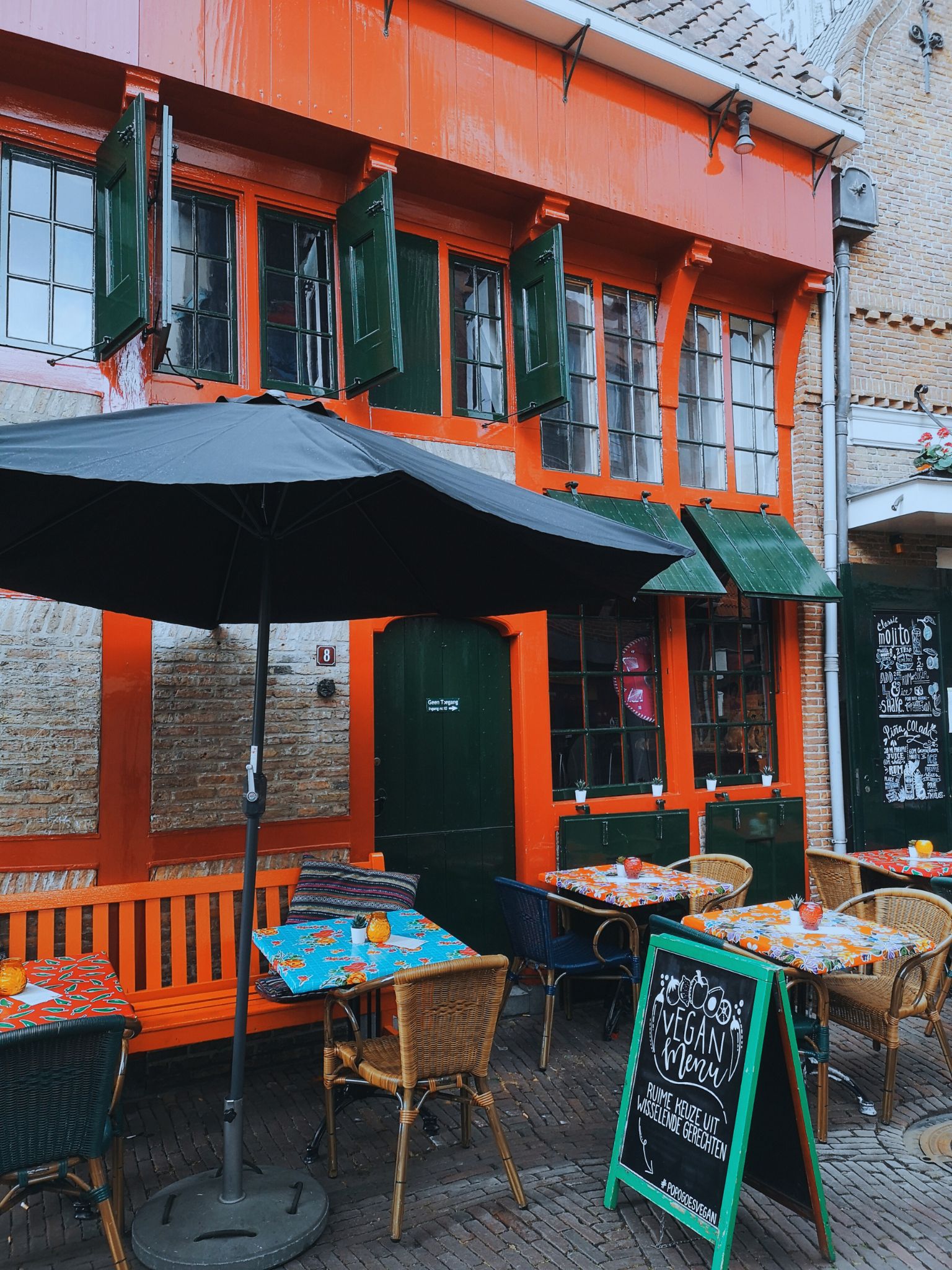 A colorful restaurant with a vegan menu sign in front of it