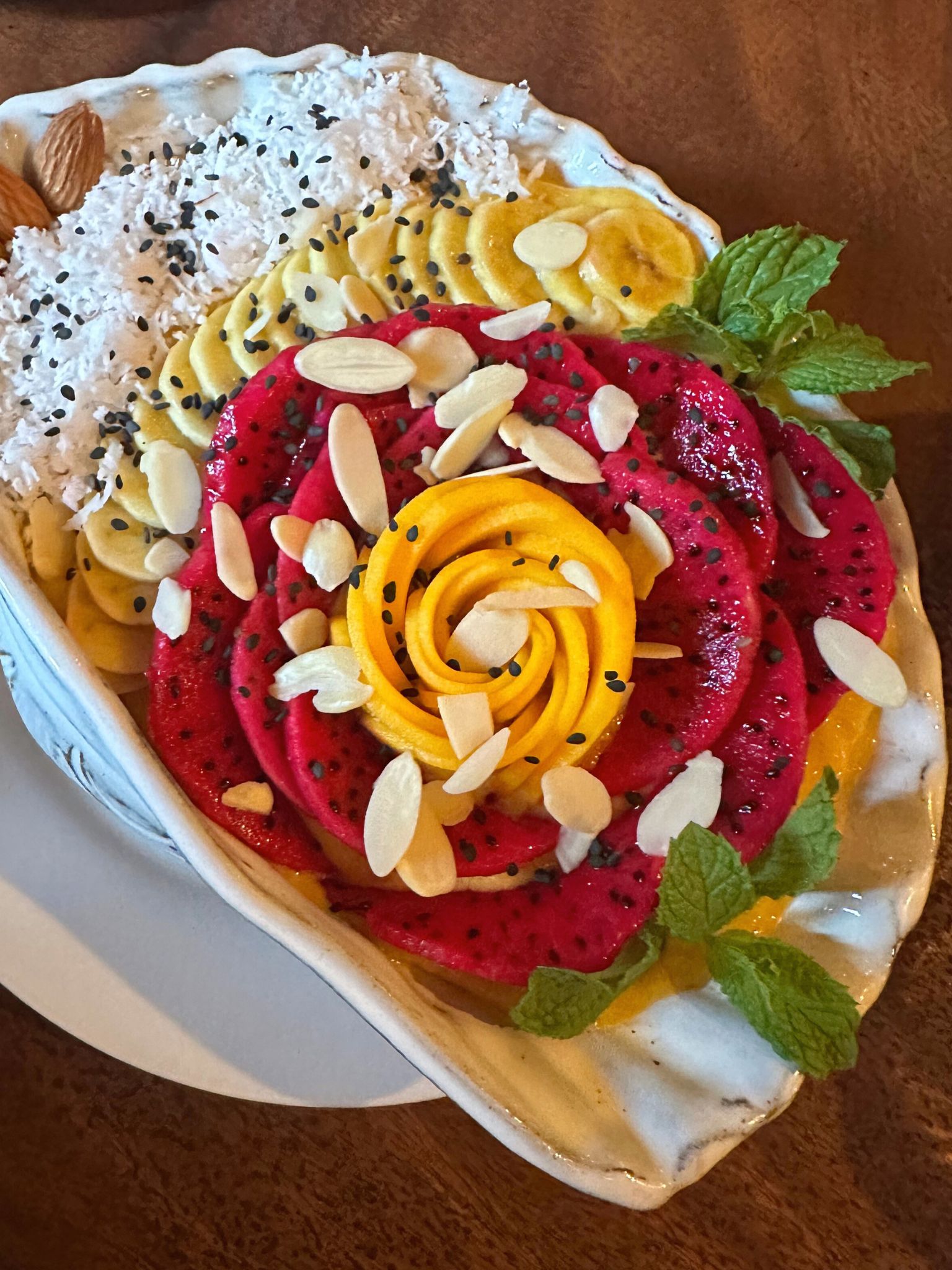 A smoothie bowl with a mango and dragonfruit shaped rose