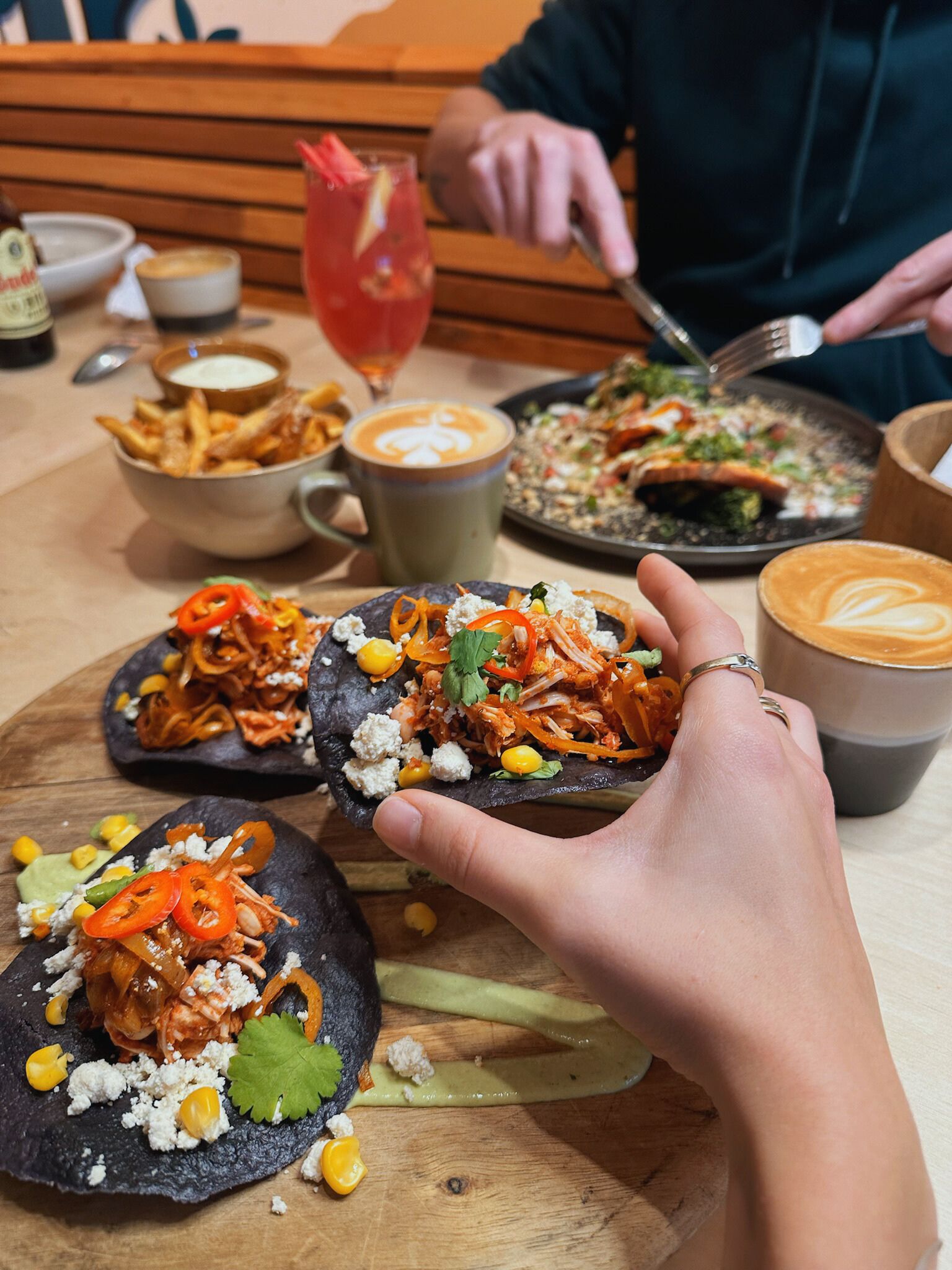 A hand holds a tostada with pulled jackfruit and feta