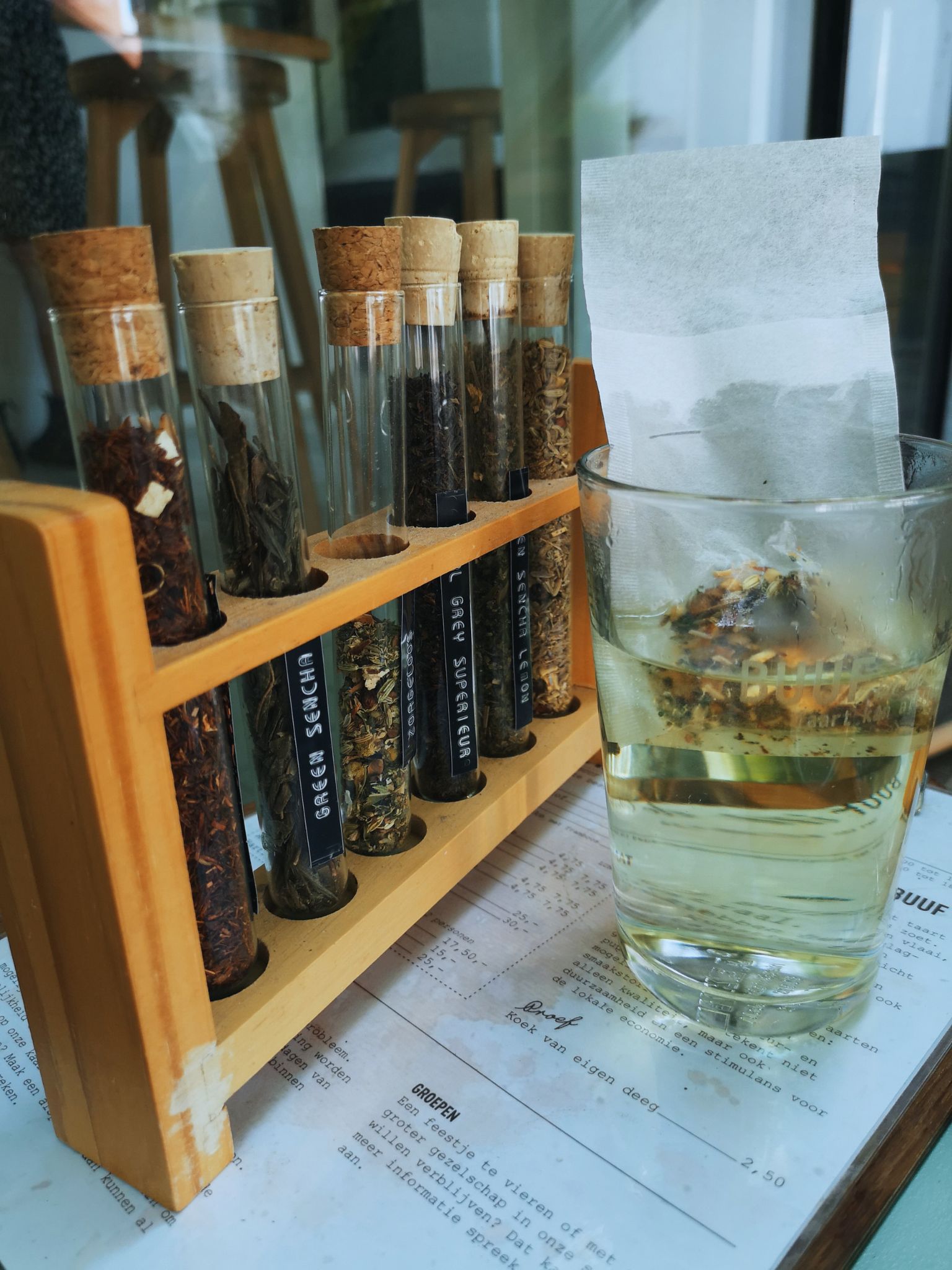 A glass with a tea bag and in the back different types of tea sustainably served