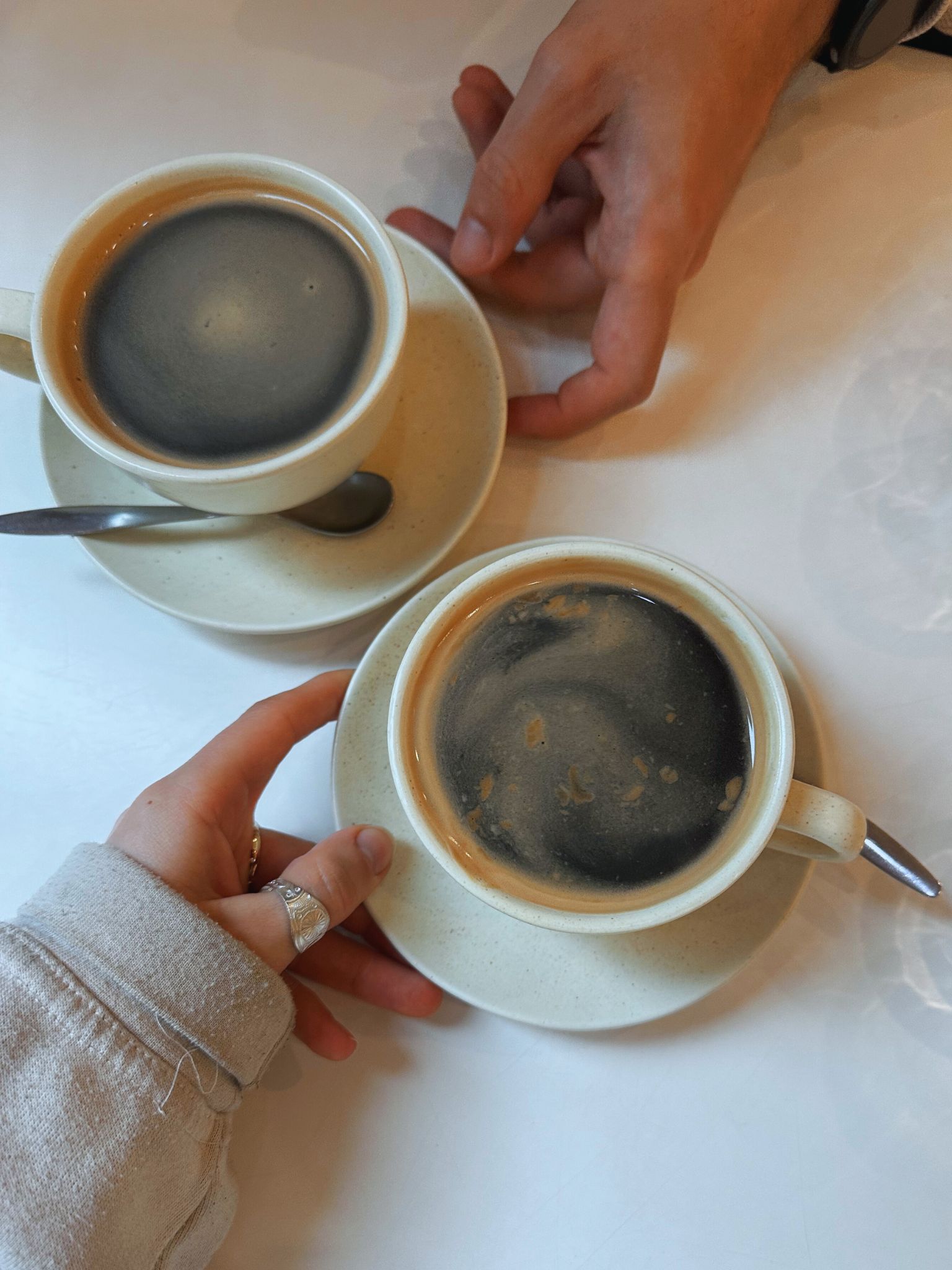 Two hands both holding a black coffee